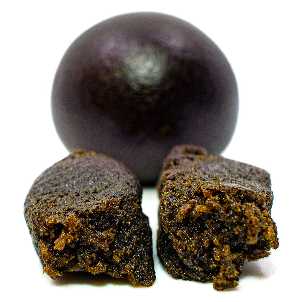 Close-up of Vortex Afghan Black Hash showing dark, dense texture with a soft, resinous interior.